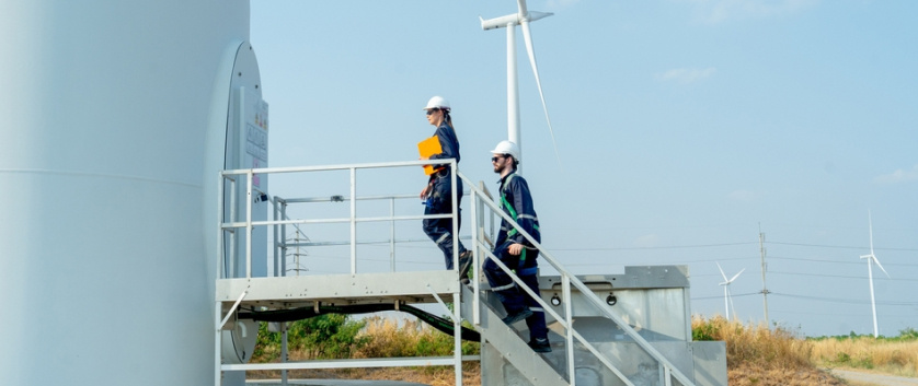 Engineers inspecting a wind turbine, highlighting solutions for supply chain management, asset lifecycle, and field engineering services.