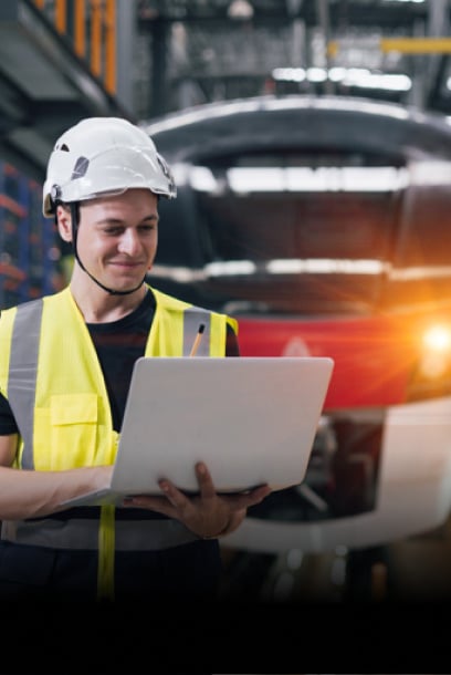 An engineer using a laptop in a railway maintenance facility, showcasing digital solutions in railway operations