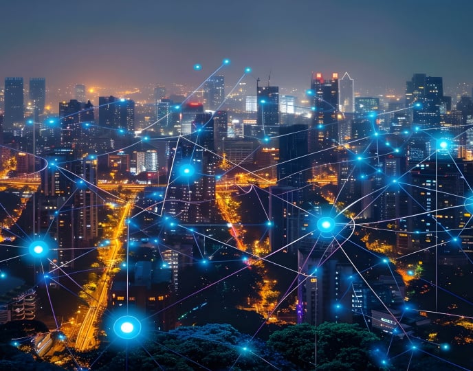 A cityscape illuminated at night with digital lines and nodes representing a connected smart grid system.