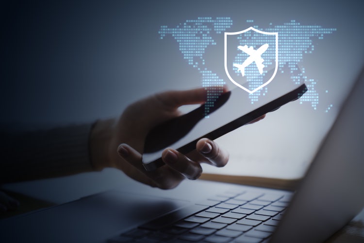 Person using smartphone for airline booking, airplane shield and world map on dark laptop background, travel security concept